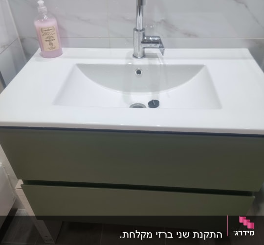 כיור עם ברז וסבון נוזלי בחדר אמבטיה
